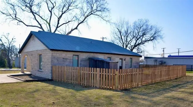 a view of a house with wooden fence and a large tree
