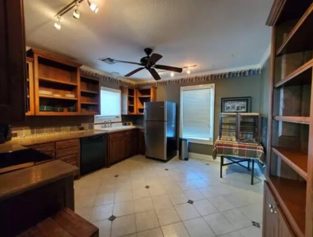 a kitchen with stainless steel appliances kitchen island granite countertop a refrigerator and a sink