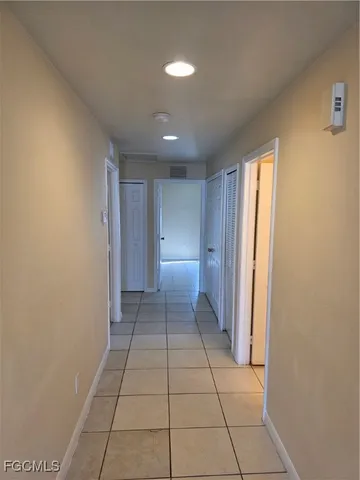 an empty room with a chandelier fan and windows