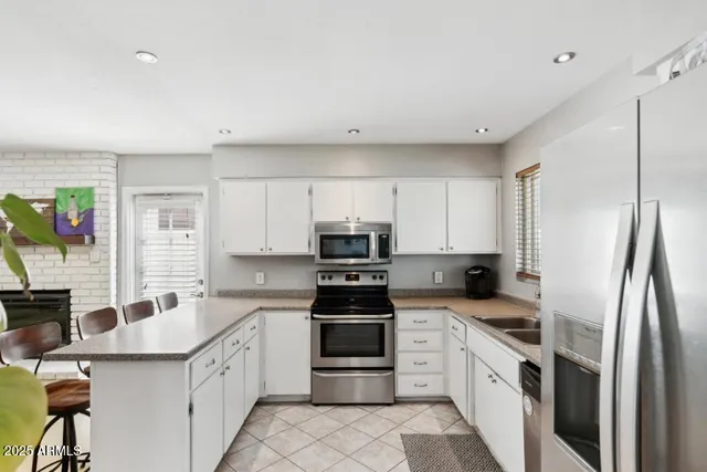 a kitchen with granite countertop a refrigerator sink and white cabinets