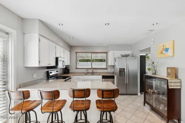 a kitchen with stainless steel appliances granite countertop a table chairs sink refrigerator and microwave