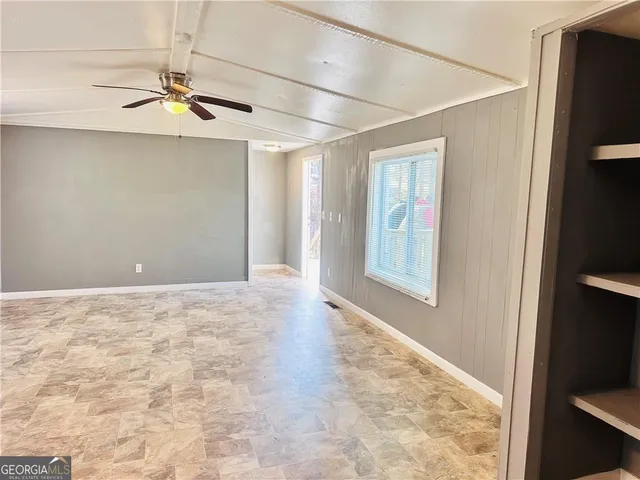 an empty room with windows and fan