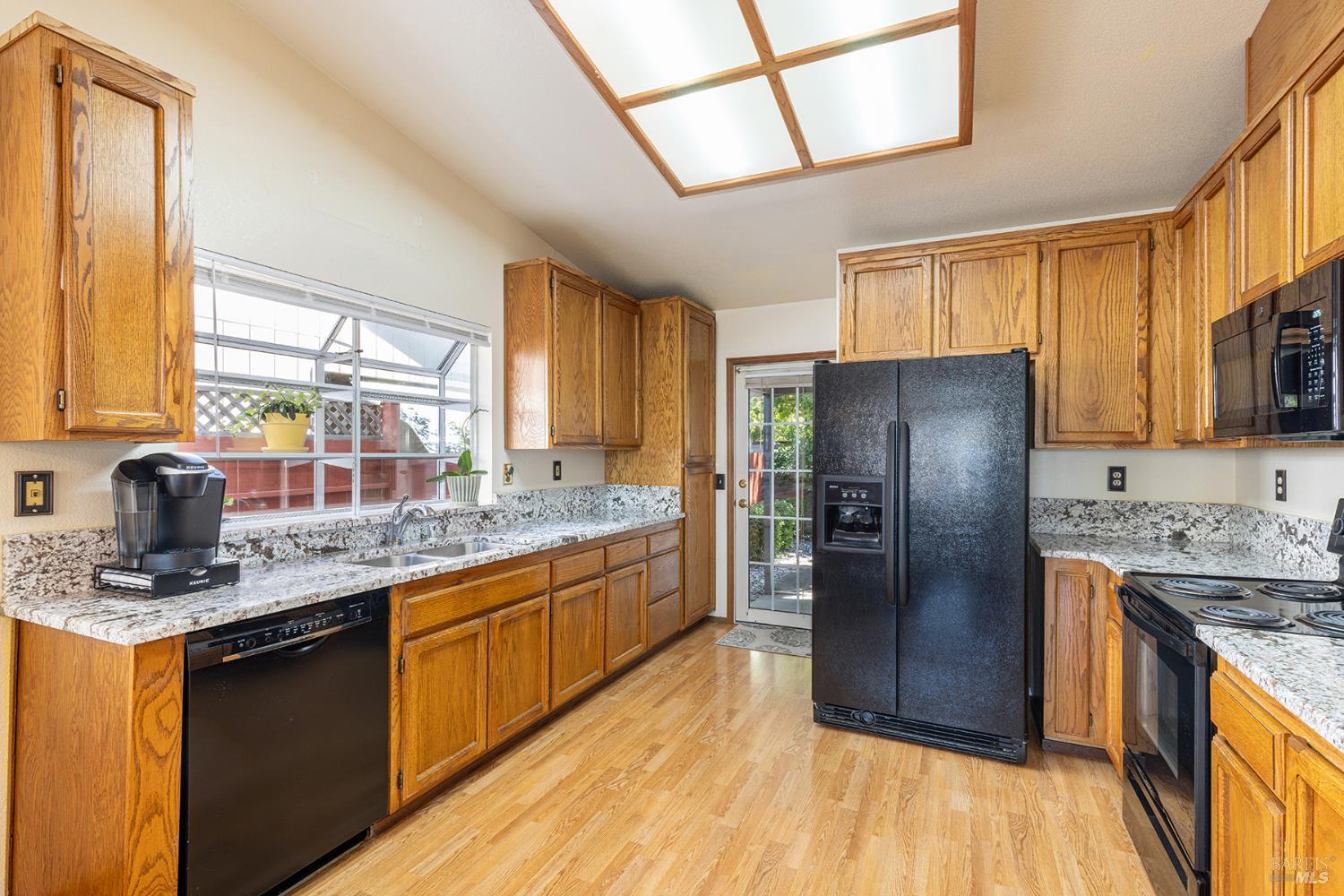 1935 Seville Street Santa Rosa, CA 95403 - Photo 9 of 30 a kitchen with stainless steel appliances granite countertop a refrigerator a sink dishwasher a stove a dining table and chairs with wooden floor