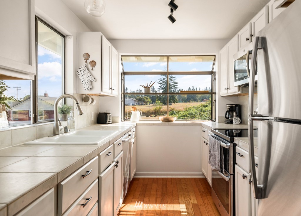 6582 Humphrey Road Clinton, WA 98236 - Photo 15 of 39 a kitchen that has a sink a window and stainless steel appliances