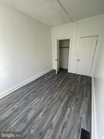 a view of an empty room with wooden floor and closet