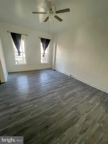 an empty room with wooden floor fan and windows