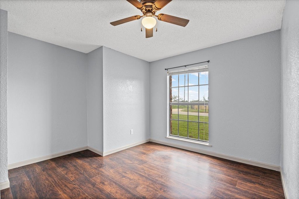 650 West Austin Street Luling, TX 78648 - Photo 13 of 18 Luminous room featuring polished wood flooring and a refreshing ceiling fan for year-round comfort.