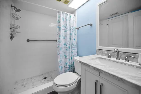 a bathroom with a granite countertop sink toilet and shower