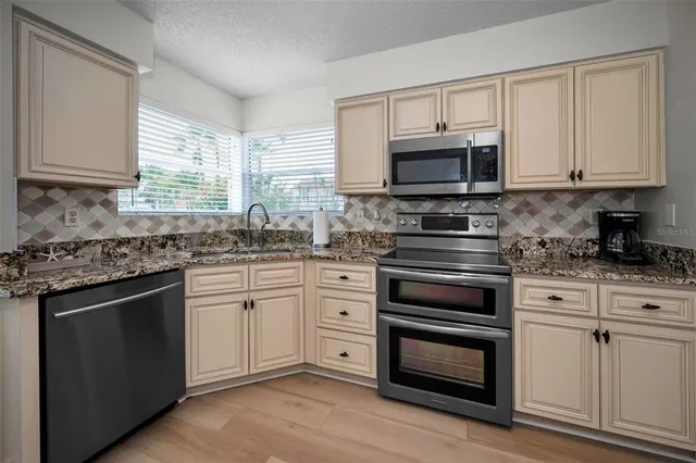 a kitchen with granite countertop a stove a sink and a microwave