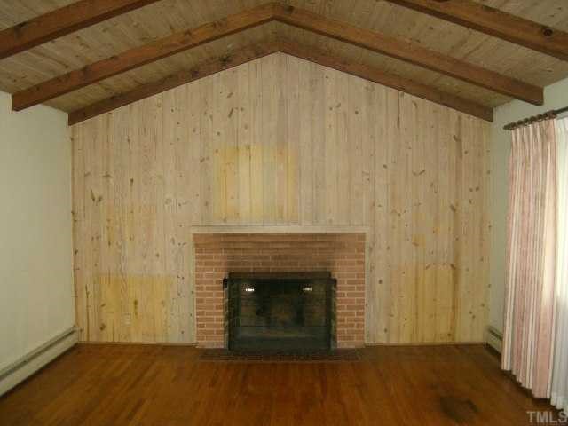 250 Winhaven Street Roxboro, NC 27573 - Photo 4 of 12 Living room has hardwood flooring, paneled walls,cathedral ceiling and fireplace