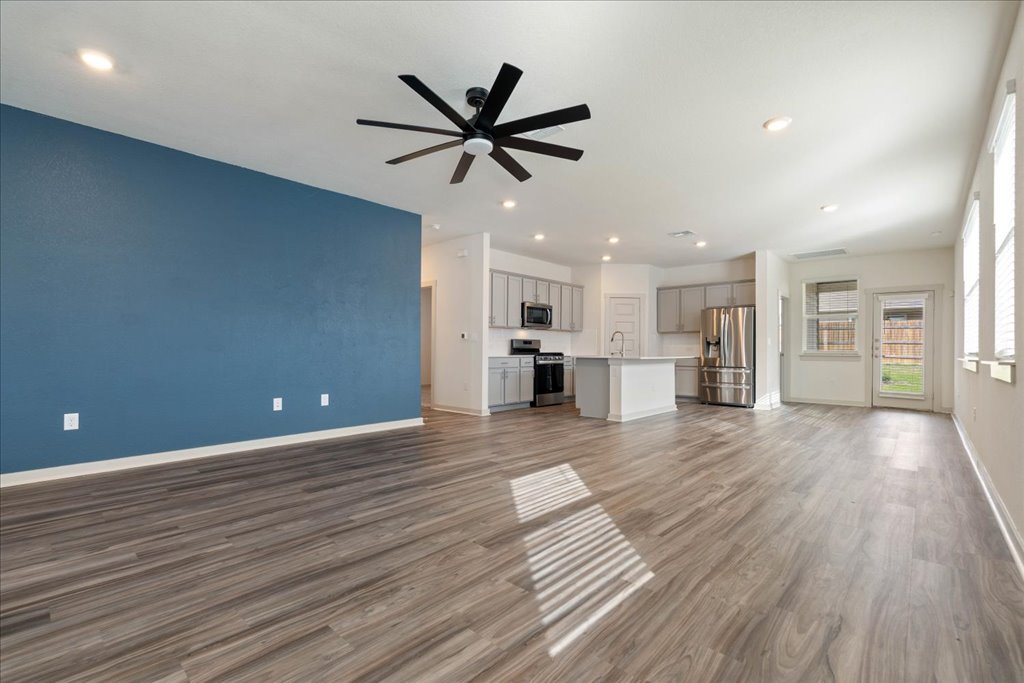7410 Sagira Path Austin, TX 78724 - Photo 7 of 37 a view of a big room with wooden floor and a kitchen