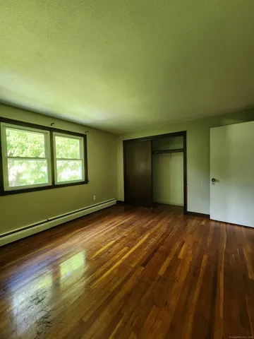 a view of an empty room with window and wooden floor