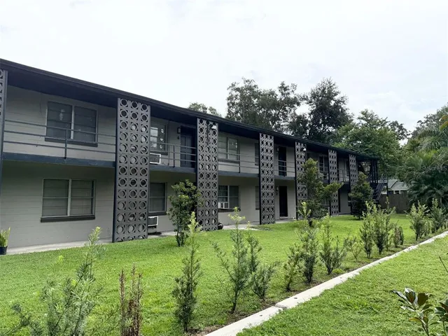 a view of a house with brick walls and a yard with plants