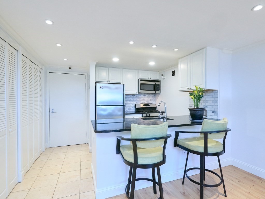 42 8th Street, Unit 5521 Boston, MA 02129 - Photo 6 of 25 a kitchen with stainless steel appliances kitchen island granite countertop a refrigerator and a stove top oven with wooden floor