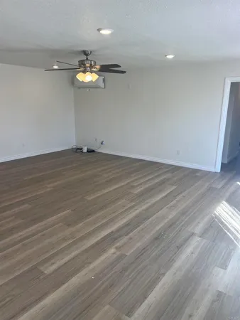 an empty room with wooden floor and fan