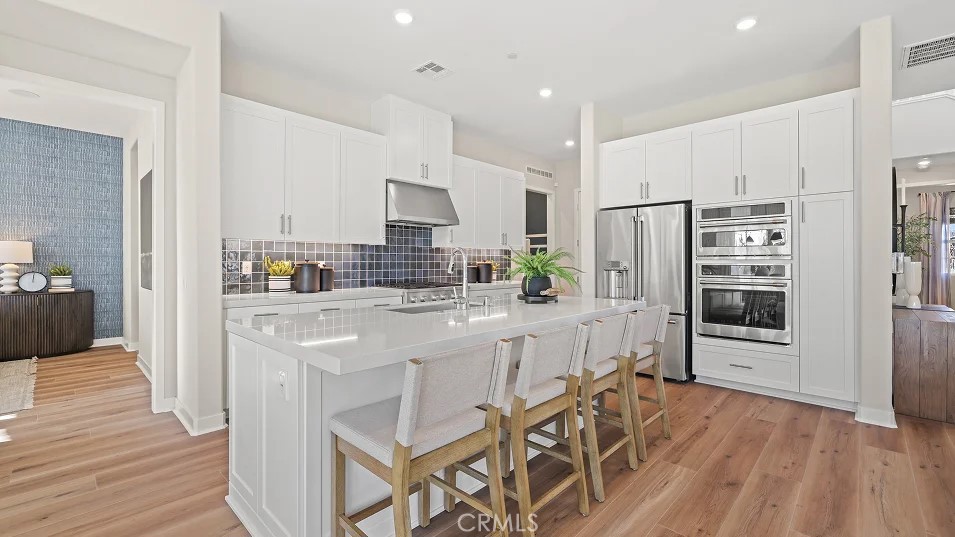 a kitchen with stainless steel appliances a refrigerator a stove a sink cabinets and wooden floor