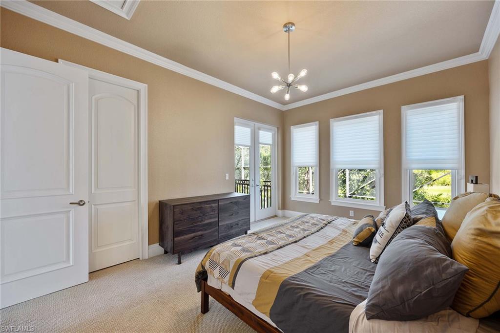 23801 Napoli Way Estero, FL 34134 - Photo 35 of 50 a spacious bedroom with a bed and a chandelier