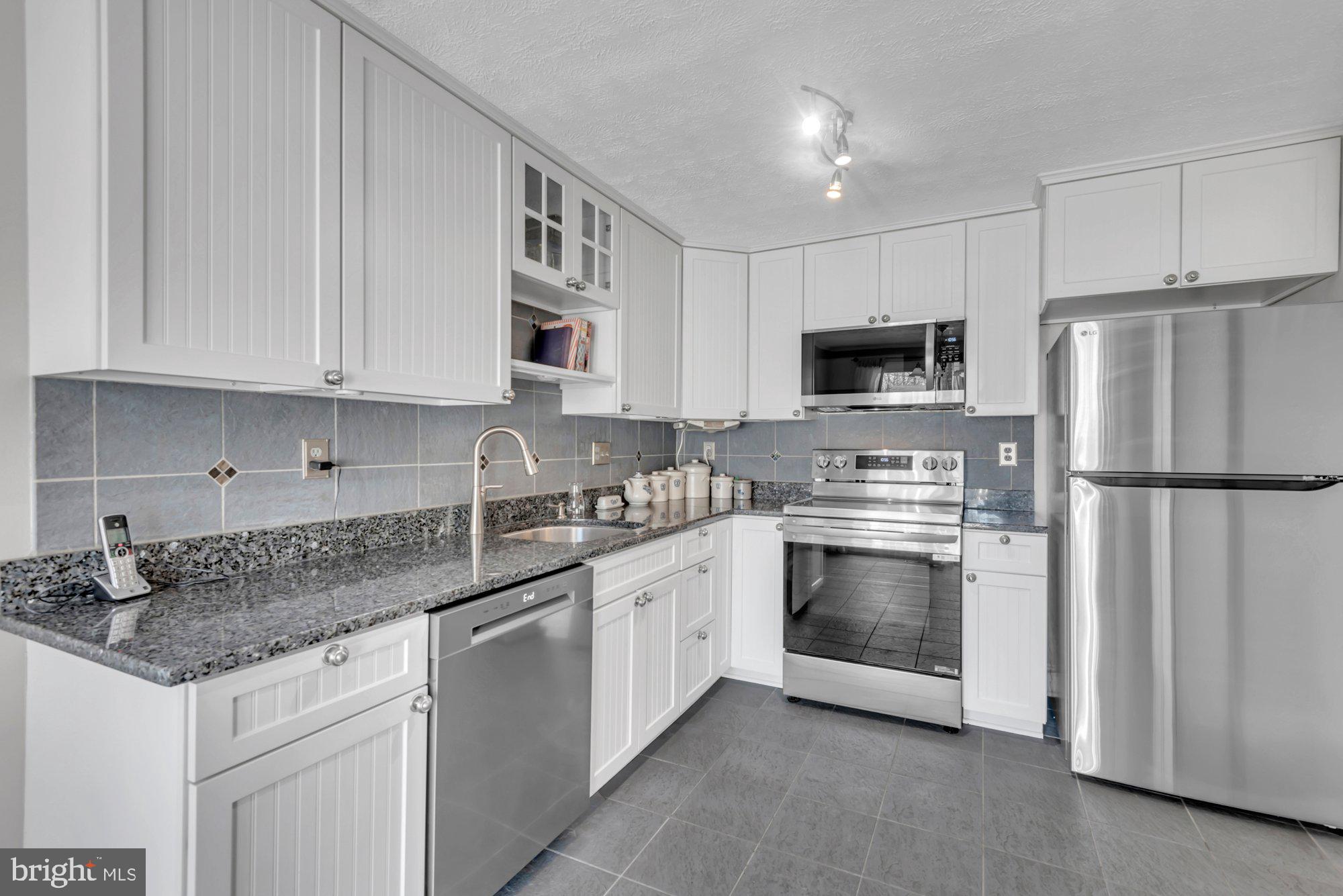 2513 Maytime Drive Gambrills, MD 21054 - Photo 9 of 40 a kitchen with granite countertop a refrigerator stove and microwave