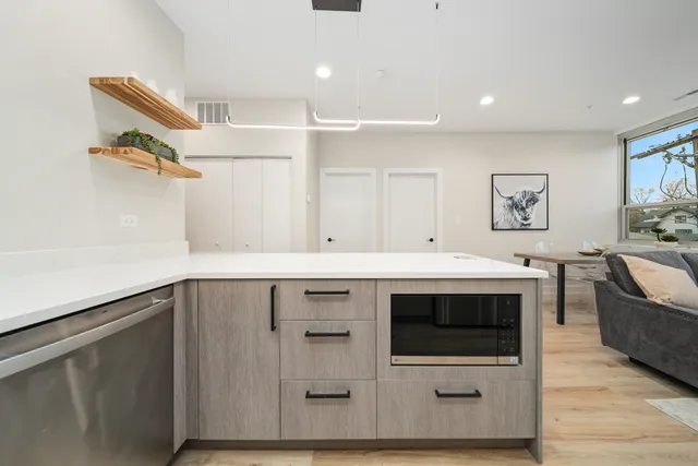 a utility room with stainless steel appliances kitchen island a stove a sink and a microwave