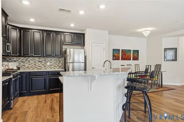 a kitchen with kitchen island a counter top space a sink stainless steel appliances and cabinets