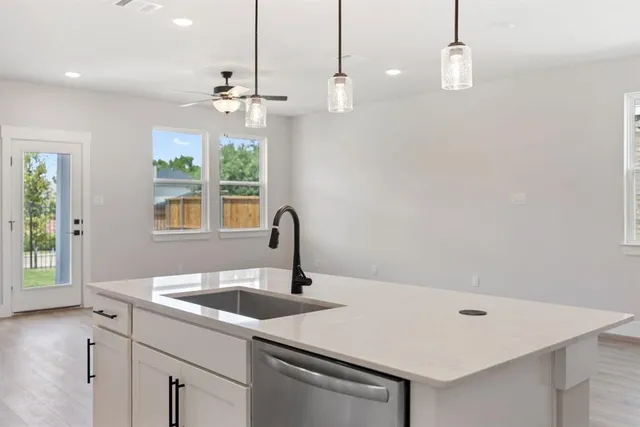 a kitchen with a sink a chandelier stainless steel appliances and windows