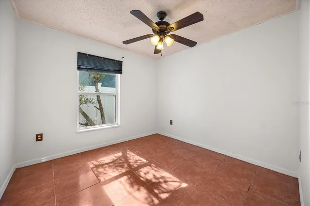 an empty room with a window and a fan