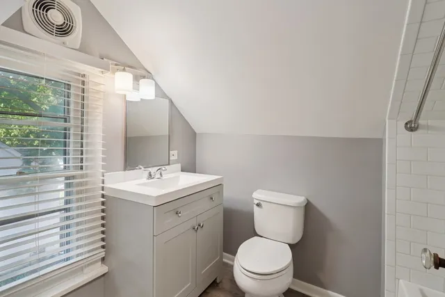 a bathroom with a toilet sink vanity and mirror