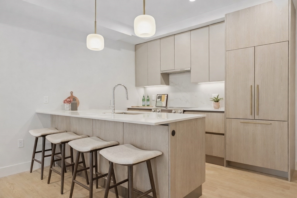 118 B Street, Unit 305 Boston, MA 02127 - Photo 2 of 10 a kitchen with stainless steel appliances chandelier a refrigerator and cabinets