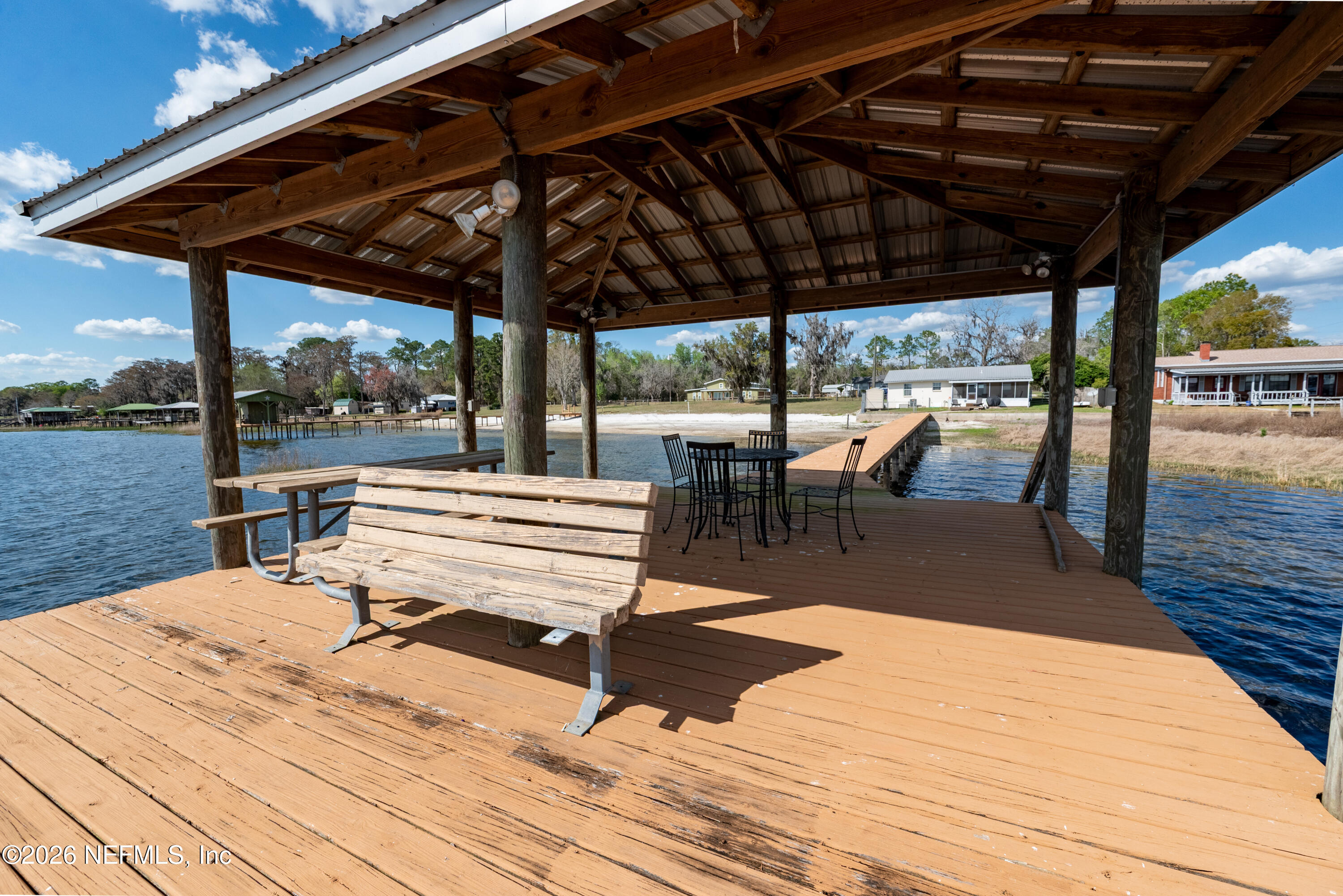 7932 Southwest County Road 18 Hampton, FL 32044 - Photo 30 of 39 a roof deck with a table and chairs under an umbrella with wooden floor