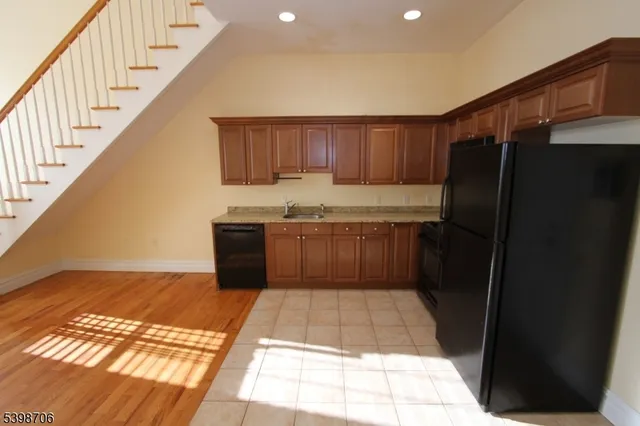a kitchen with a sink a refrigerator and black cabinets
