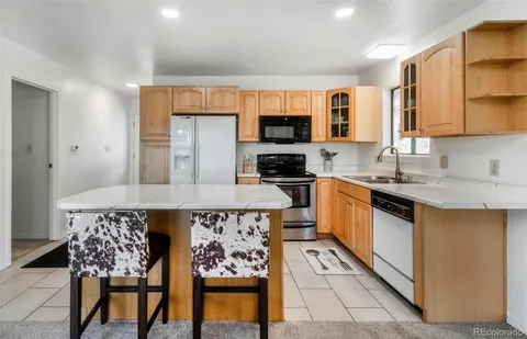 a kitchen with stainless steel appliances granite countertop a stove top oven a sink a dining table and chairs with wooden floor