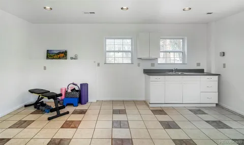 a kitchen with a sink a stove and white cabinets with wooden floor