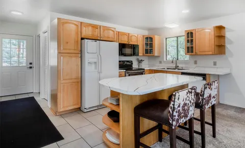 a kitchen with a sink a refrigerator and chairs