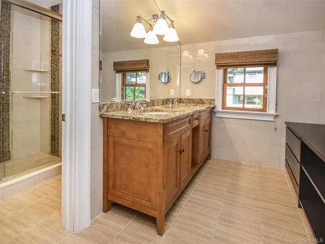 a bathroom with a granite countertop sink a mirror and a bathtub next to a window