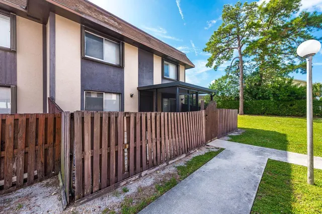 a view of a house with backyard and porch with wooden fence