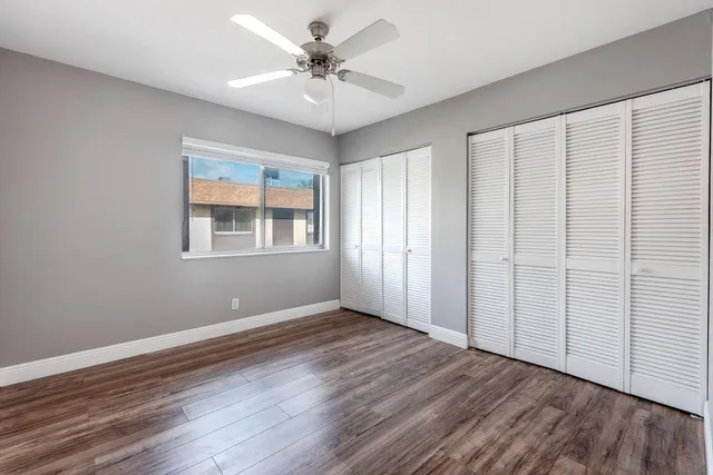 a view of an empty room with a window and wooden floor