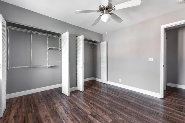 an empty room with wooden floor closet and windows