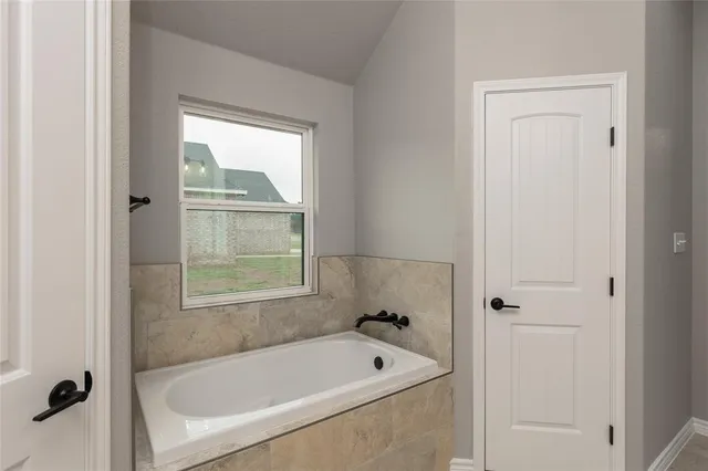 a bathroom with a tub shower and a window