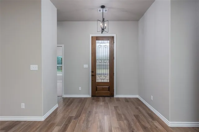 an empty room with wooden floor cabinet and windows