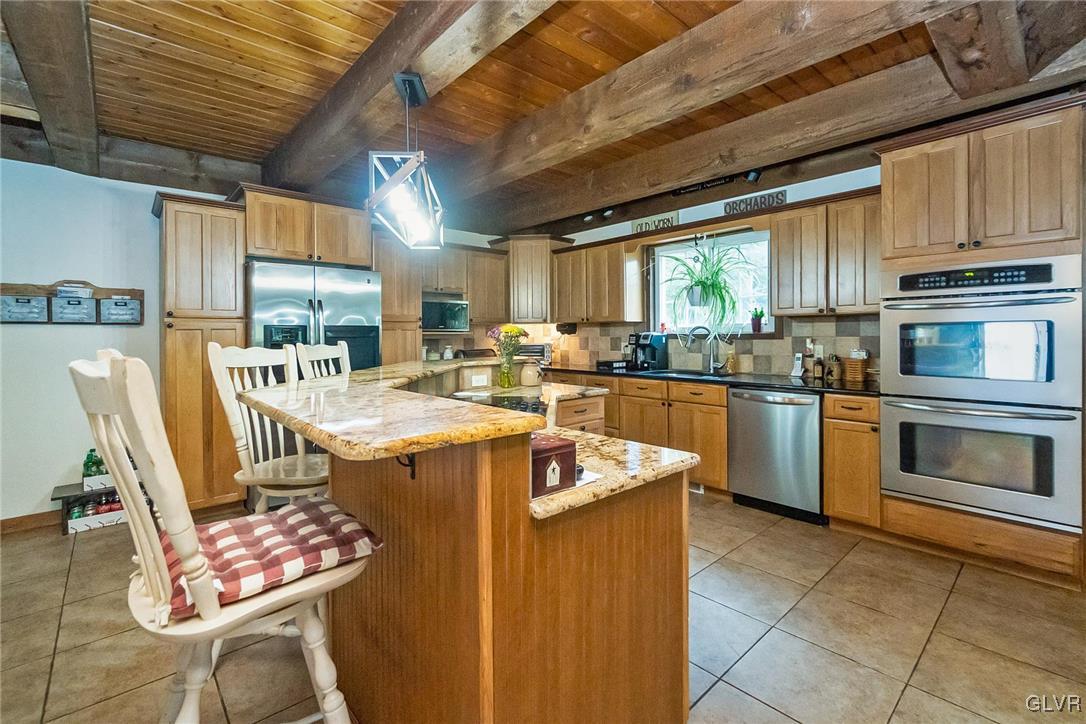 115 Pine Cove Court Lehighton, PA 18235 - Photo 30 of 49 a kitchen with stainless steel appliances kitchen island granite countertop a table chairs and a wooden cabinets