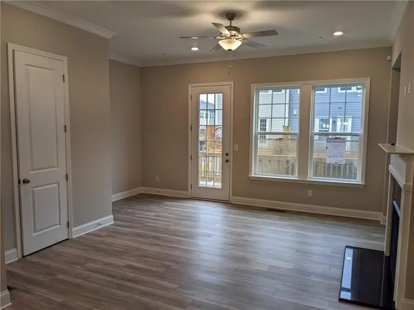 a view of an empty room with wooden floor and a window
