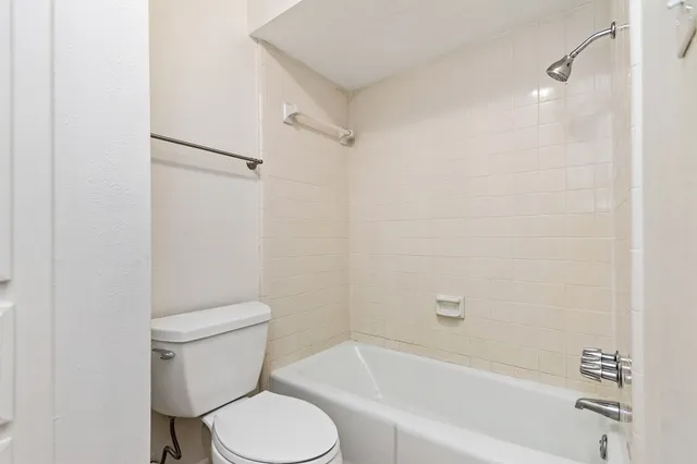 a white toilet sitting next to a bath tub