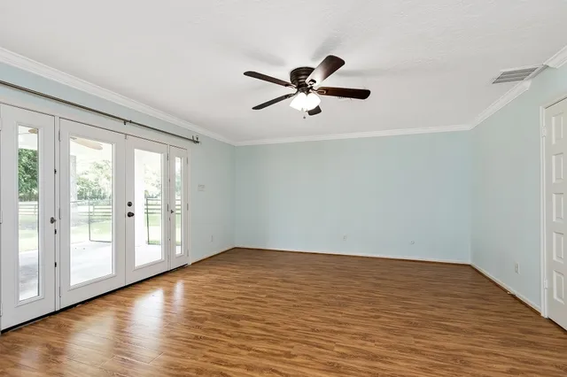 a view of empty room with wooden floor and fan