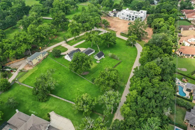 an aerial view of residential houses with outdoor space and trees