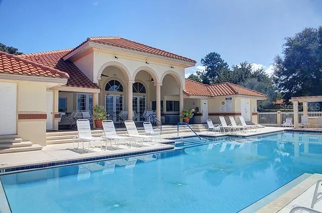 a view of a white building with couches chairs and a swimming pool view