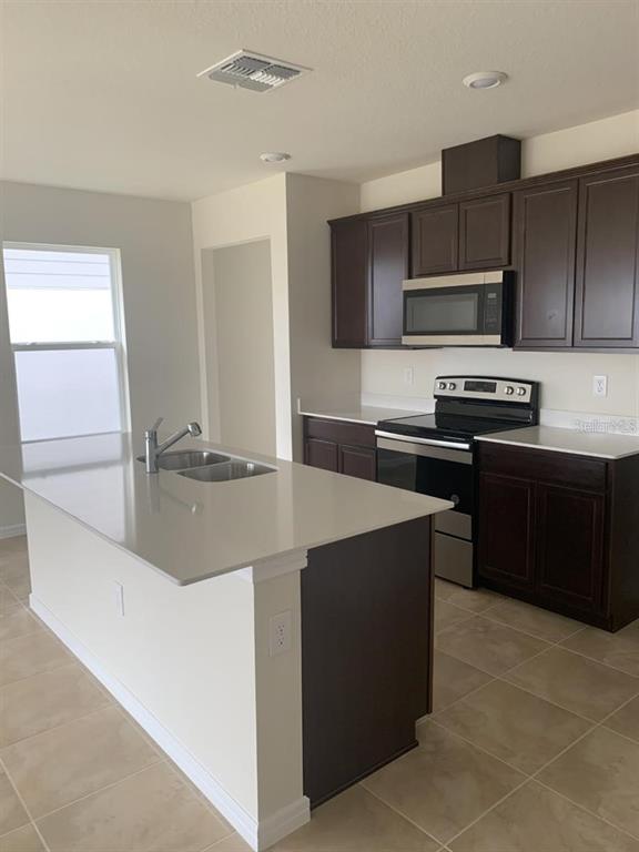 7363 Catania Loop Clermont, FL 34714 - Photo 5 of 12 a kitchen with stainless steel appliances a sink stove and refrigerator