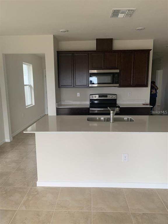 7363 Catania Loop Clermont, FL 34714 - Photo 7 of 12 a kitchen with kitchen island a sink a microwave and cabinets