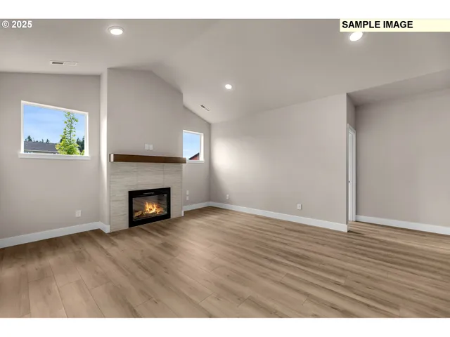 a view of an empty room with wooden floor and a fireplace