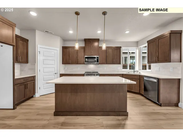 a large kitchen with kitchen island a large counter top space a sink stainless steel appliances and cabinets