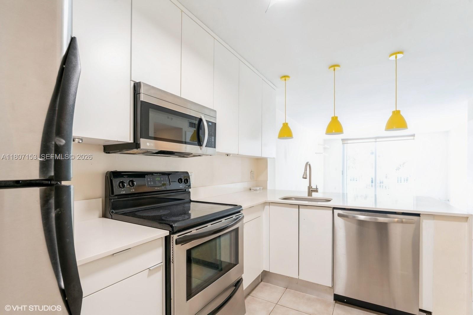 750 Northeast 64th Street, Unit B308 Miami, FL 33138 - Photo 4 of 25 a kitchen with stainless steel appliances a stove a microwave and a refrigerator
